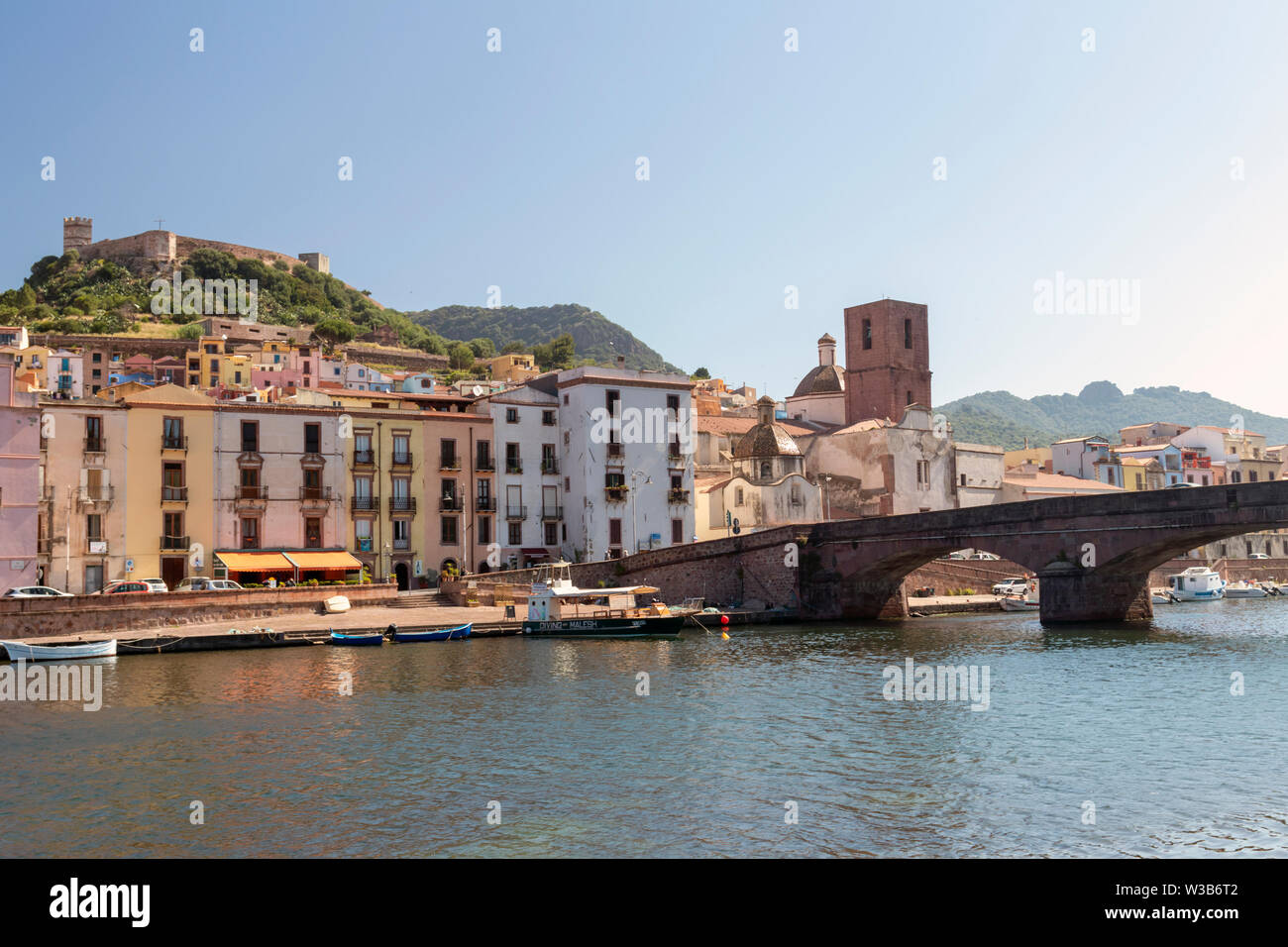 View of Bosa, Sardinia, with colorful Italian houses and castle on hilltop. River Temo with bridge in foreground. Summer day shot. Stock Photo