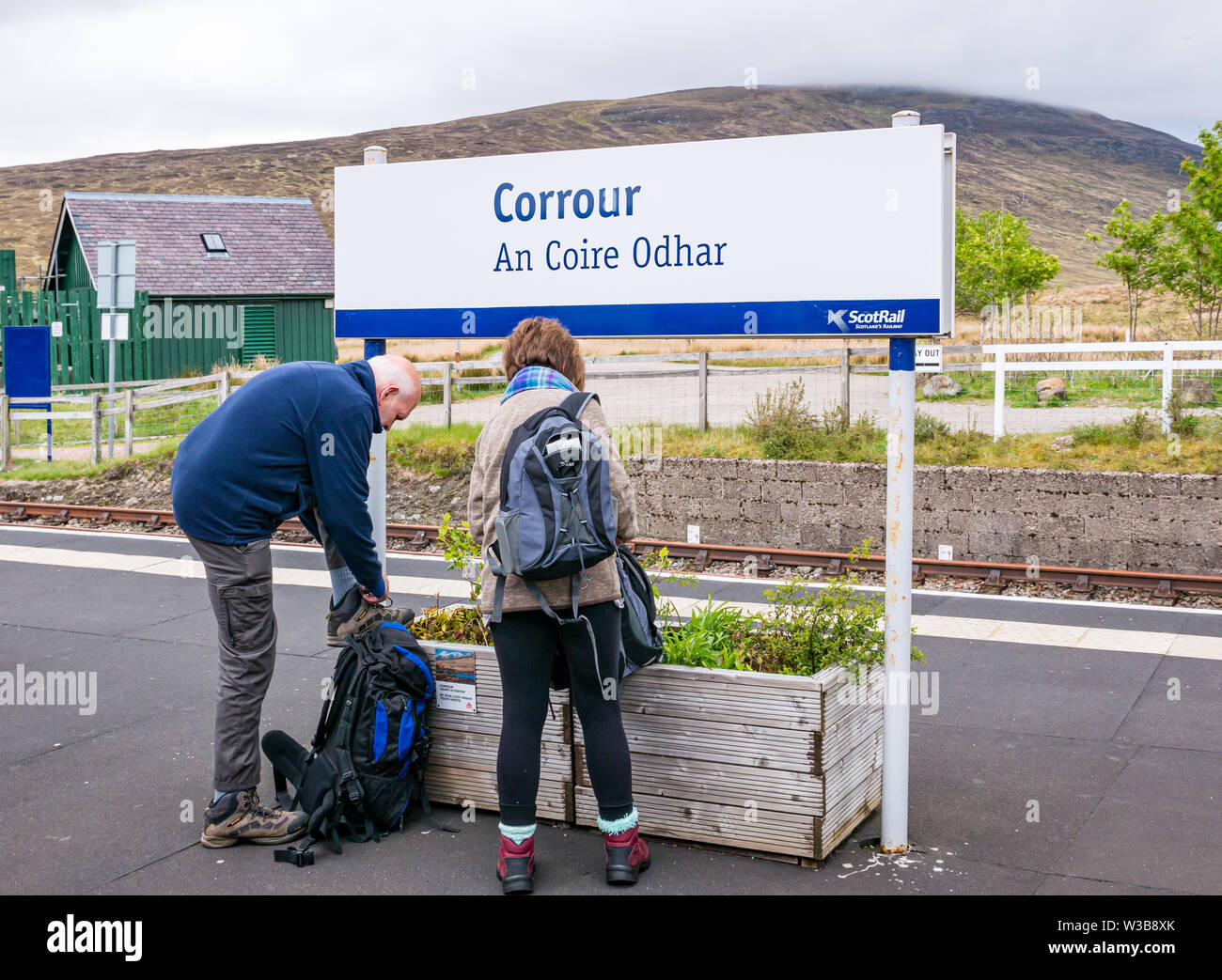 ScotRail Corrour rural train station platform name sign with walkers on