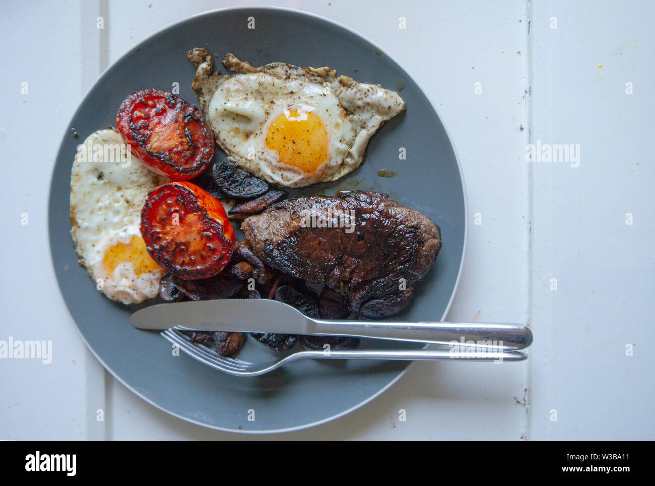 Overhead view of a plate of steak and eggs and fried tomato Stock Photo