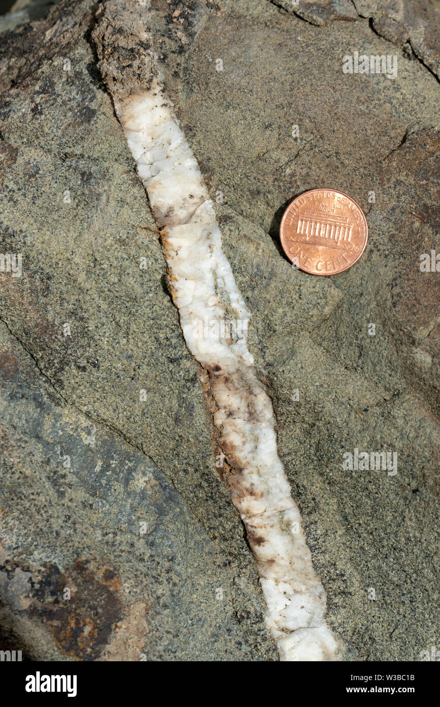 Close-up view of calcite vein in sandstone. USA penny for scale. Stock Photo