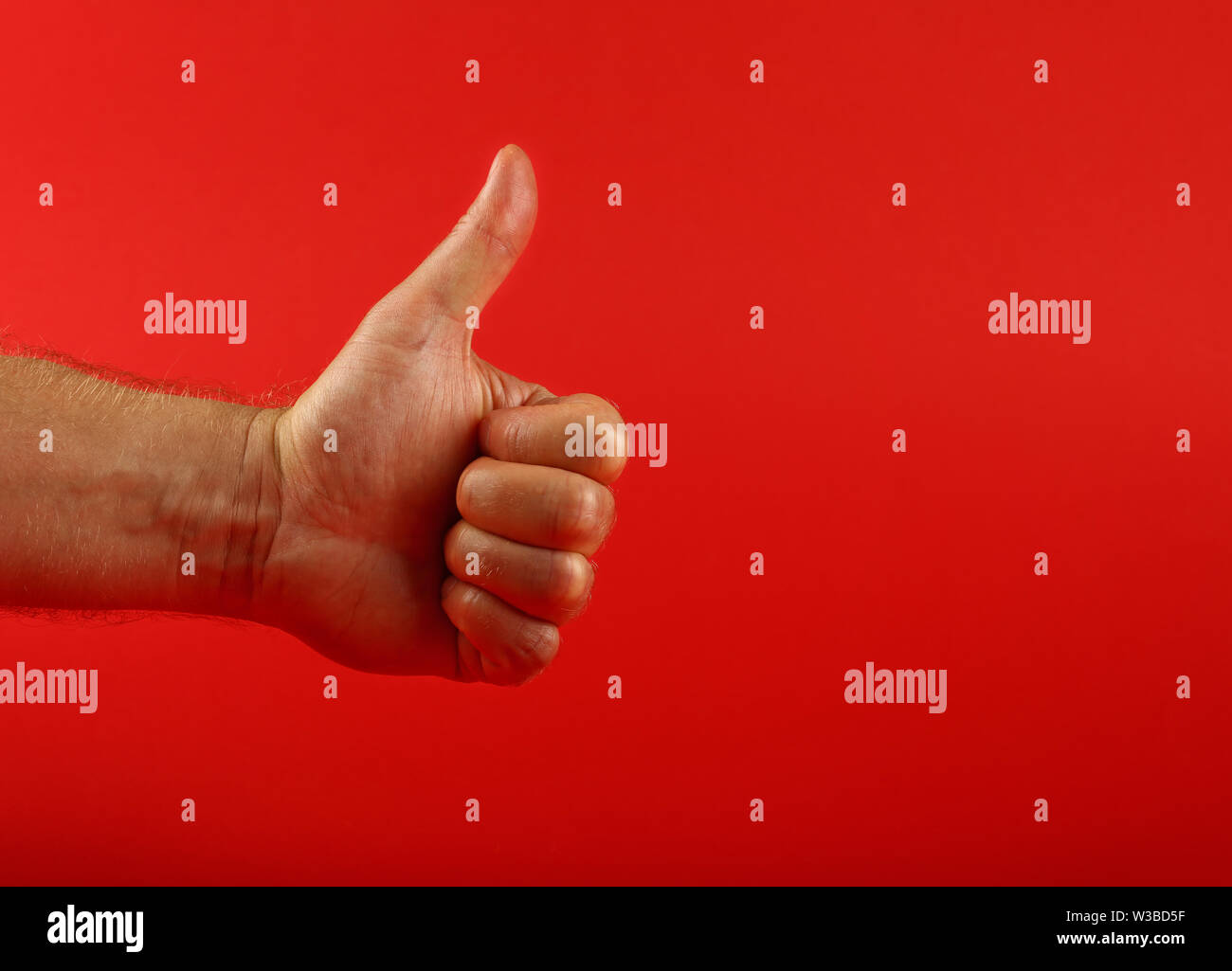 Man hand shoving thumb up ok good gesture over red background, side ...