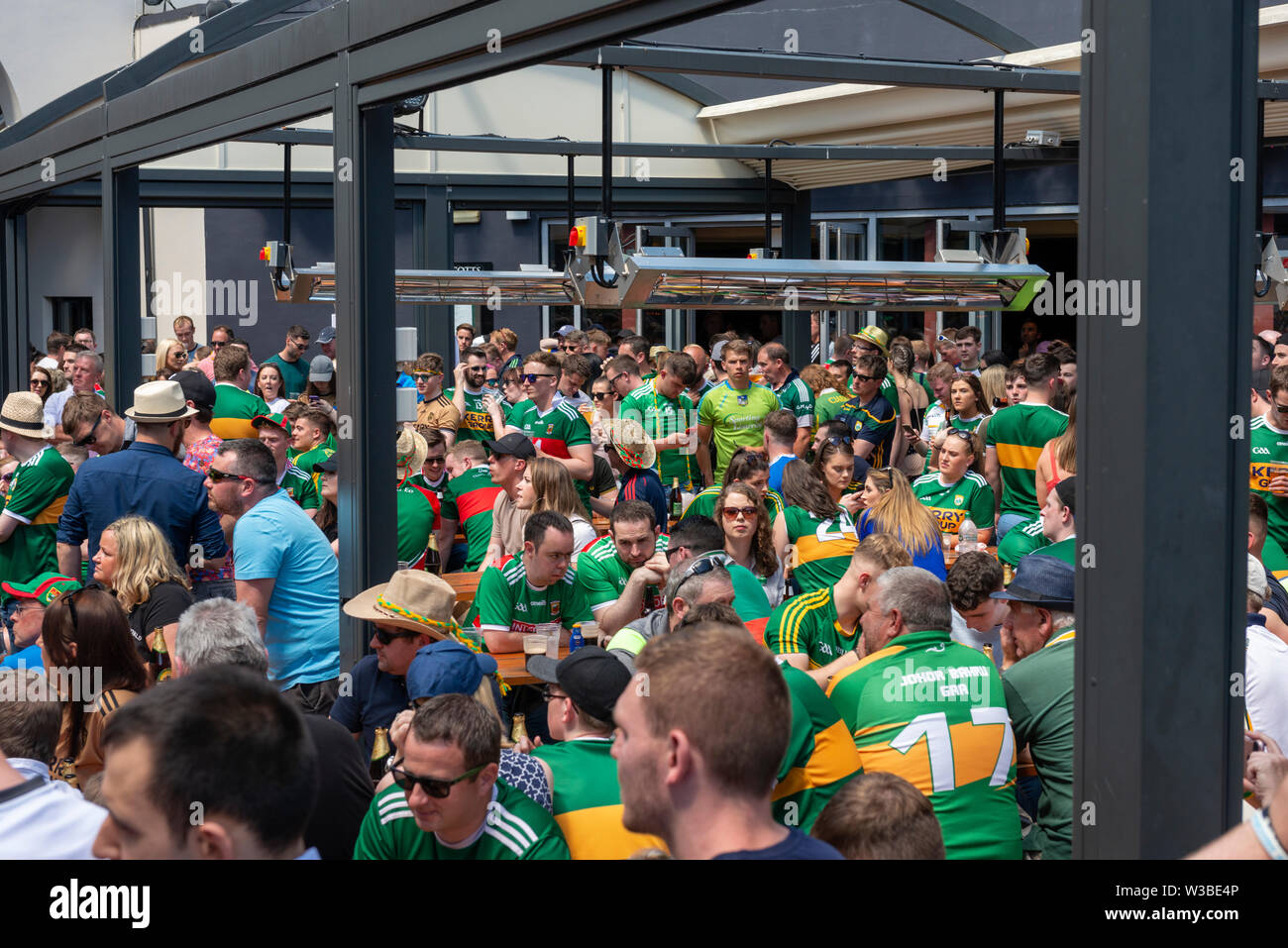 Busy Irish town. Match day in Killarney, County Kerry, Ireland. Kerry  Gaelic football fans supporters in green and yellow jerseys during the Mayo  and Kerry game in July 2019 enjoying the sunshine