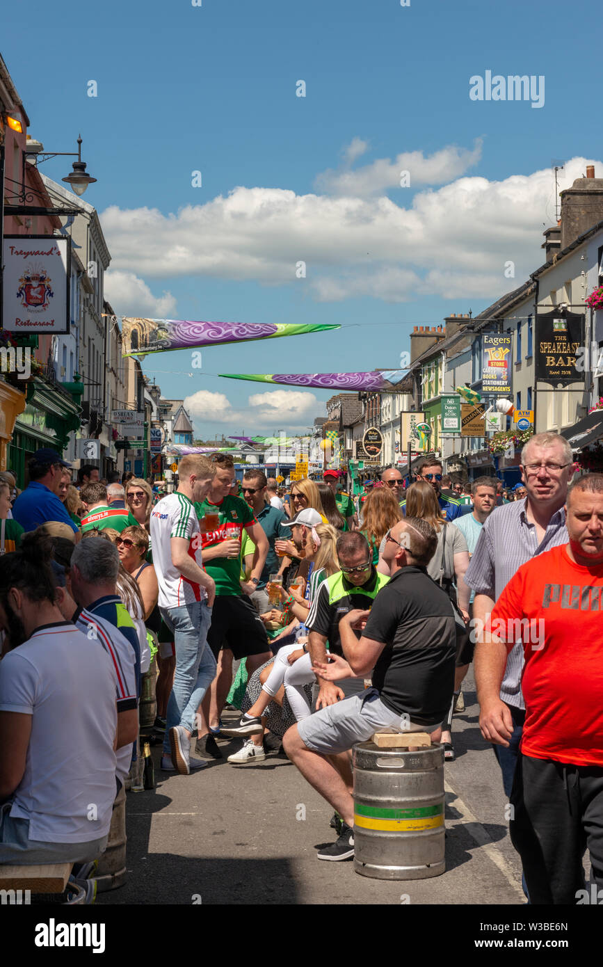 Matchday in Killarney, County Kerry, Ireland. Crowd of Gaelic football fans supporters on a match day in High Street before the Mayo and Kerry game in July 2019. Busy Irish town. Stock Photo