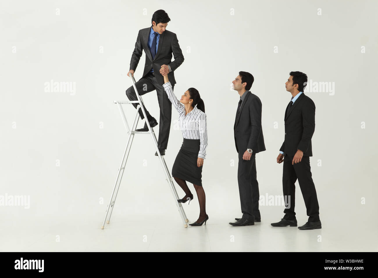 Businessman helping his colleagues to climbing step ladder Stock Photo