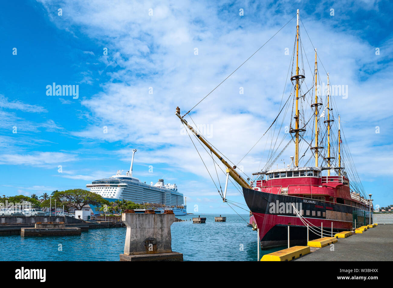 Honolulu, Awaii - May 3, 2019: An ancient sail boat with a cruise ship in the background in the Honolulu harbor Stock Photo