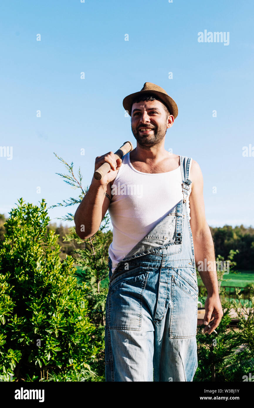 Smiling young farmer man standing in the garden while looking away Stock  Photo - Alamy