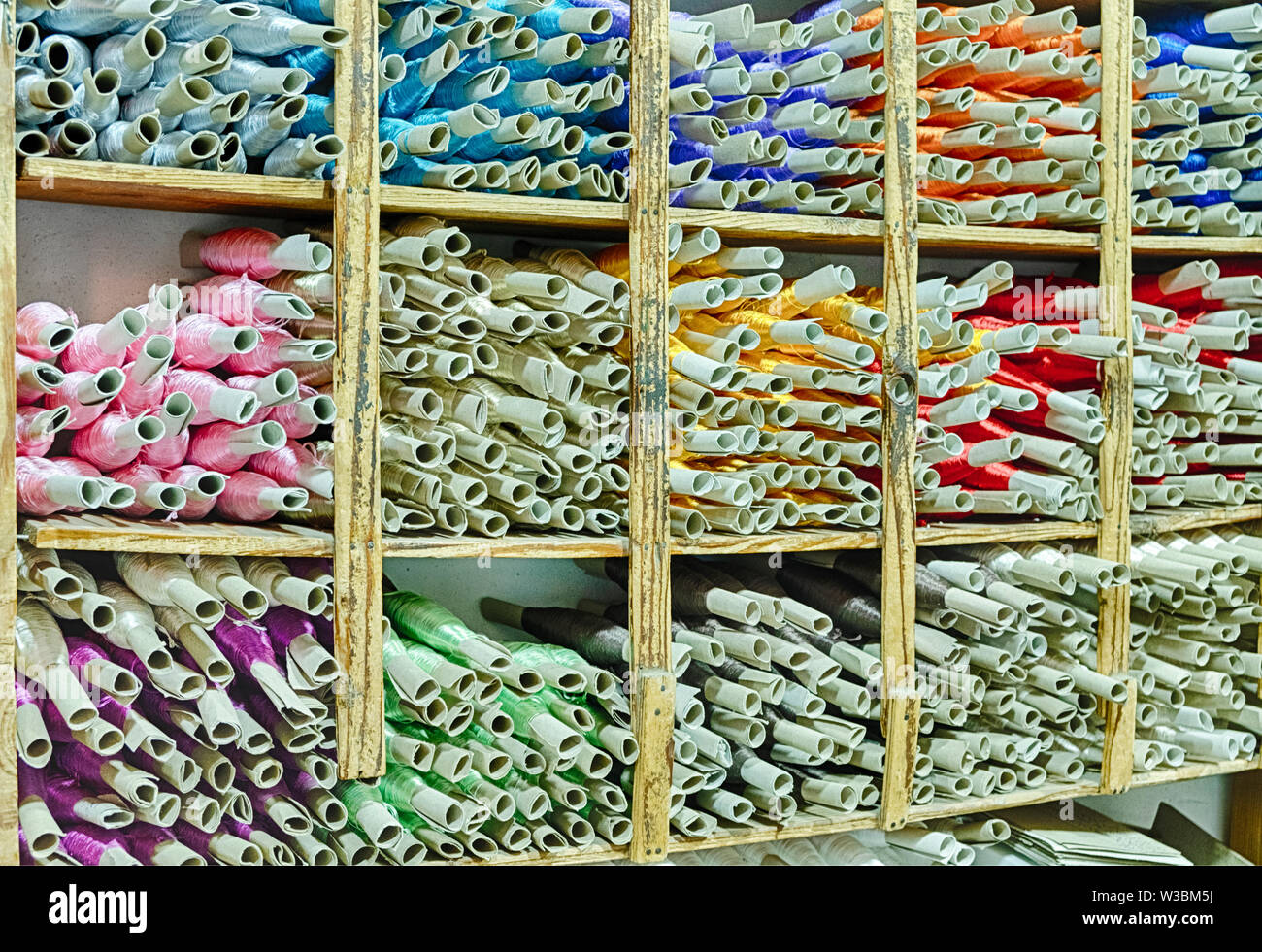 Shelves of brightly colored thread fill the shop of a sewing shop in ...