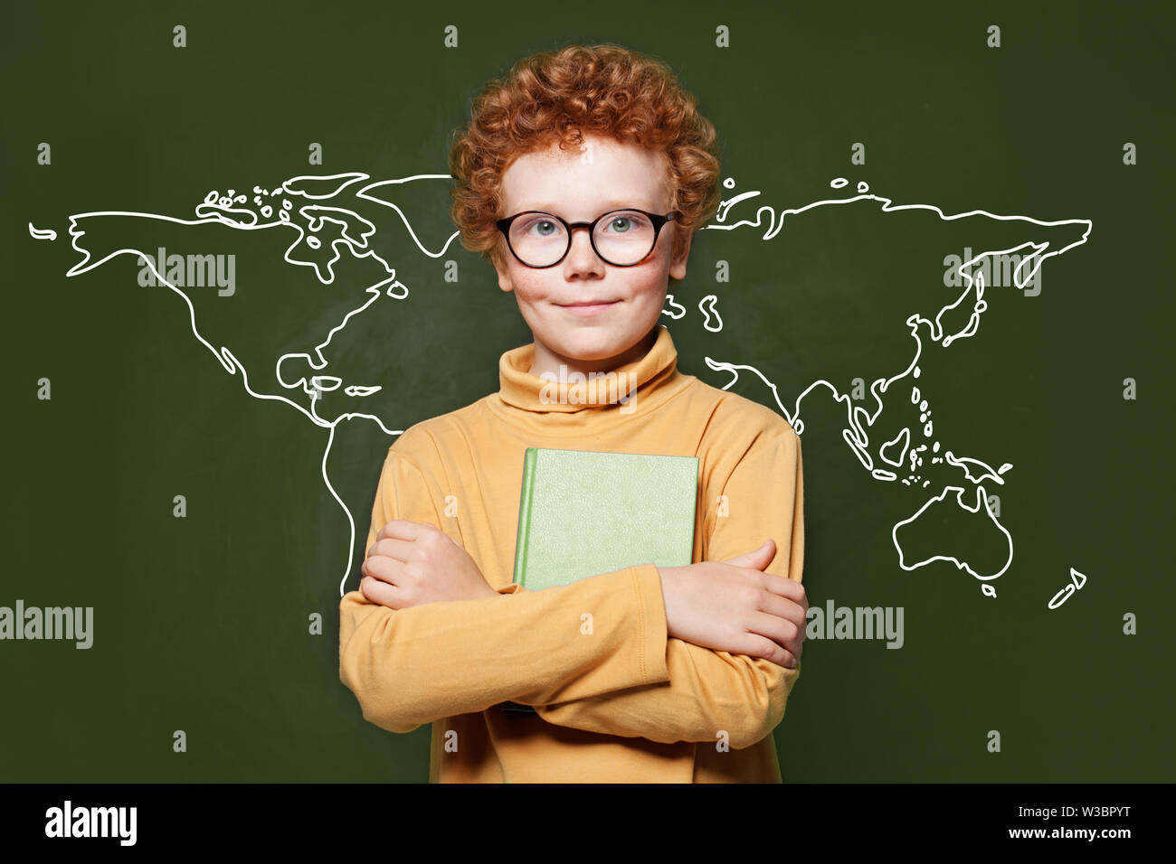 Smart child boy with map of Earth on green chalkboard. Environmental
