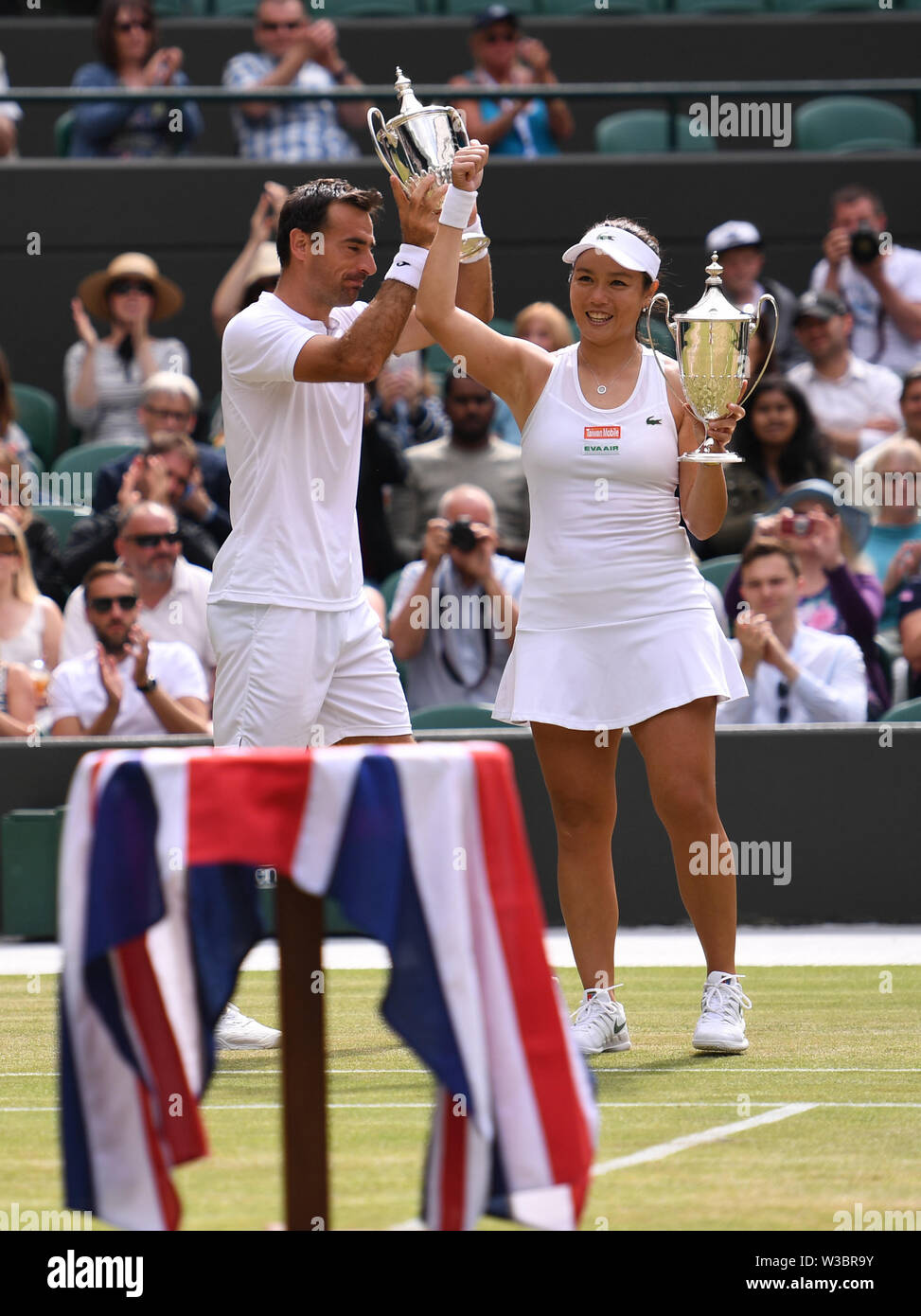 London, UK. 14th July, 2019. Ivan Dodig (L) of Croatia and Latisha Chan of  Chinese Taipei lift up their trophies after winning the mixed doubles final  match against Robert Lindstedt of Sweden