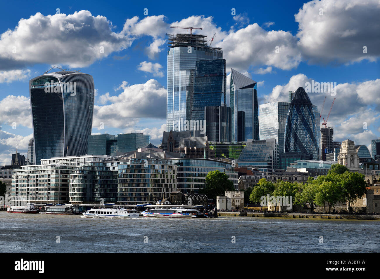 Tower Pier with tour boats on the River Thames financial district skyscrapers Walkie Talkie Cheesegrater Scalpel and the Gherkin London England Stock Photo
