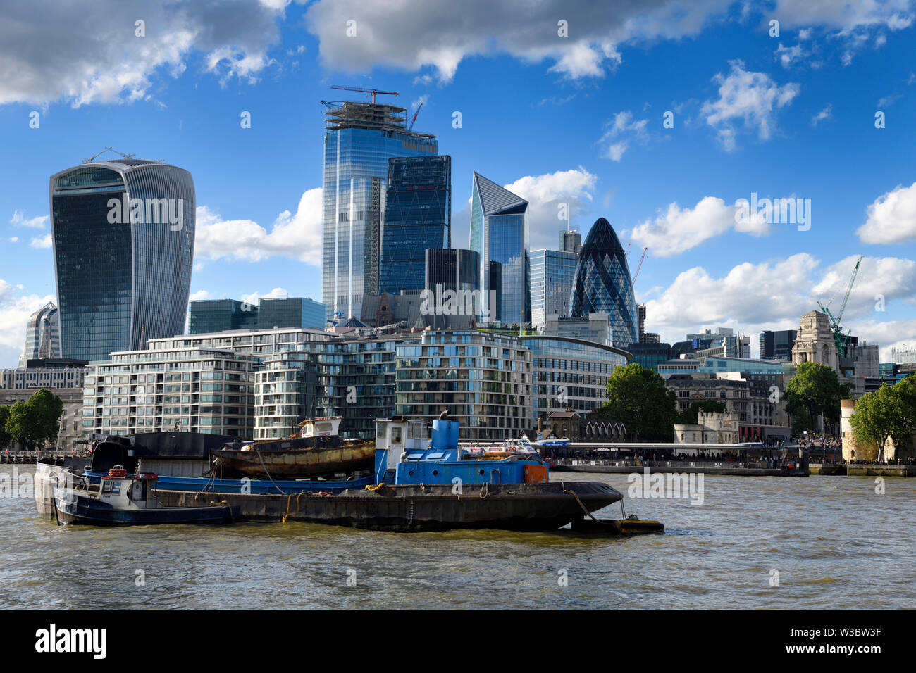 Towing barge Eileena tug boat on the River Thames with shiny glass highrise towers of the financial district in London England Stock Photo
