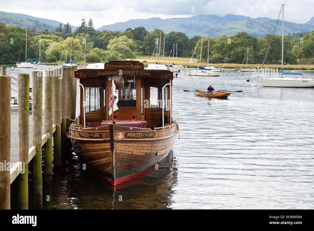 Ambleside, Cumbria, UK. 14th July 2019. UK weather - a cloudy day for visitors enjoying the boats on Lake Windermere arriving in Ambleside, Cumbria in the Lake District.  Tomorrow is forecast to be a brighter day Credit: Kay Roxby/Alamy Live News Stock Photo