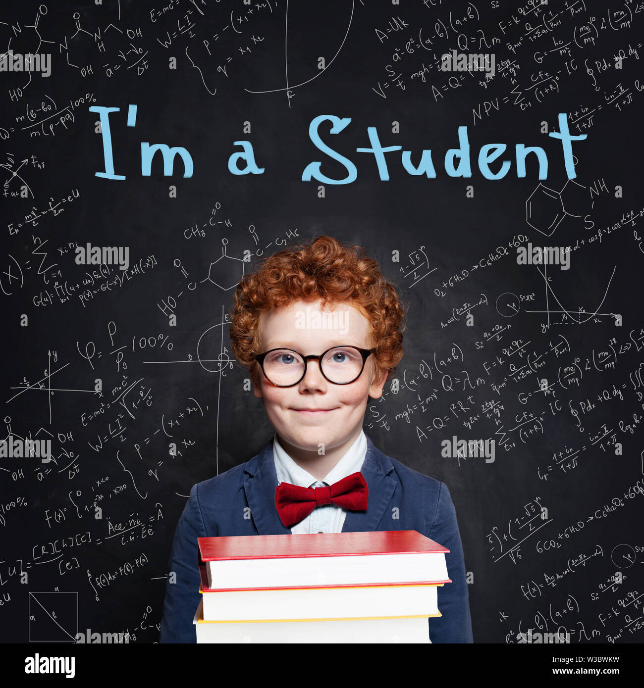 Cute Child Boy With Ginger Hair Holding Books In Classroom On
