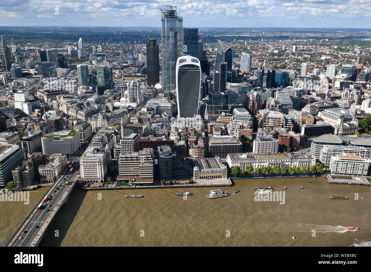 Aerial view of financial district skyscrapers unfinished Bishopsgate Walkie Talkie Cheesegrater Scalpel on muddy River Thames at London Bridge England Stock Photo