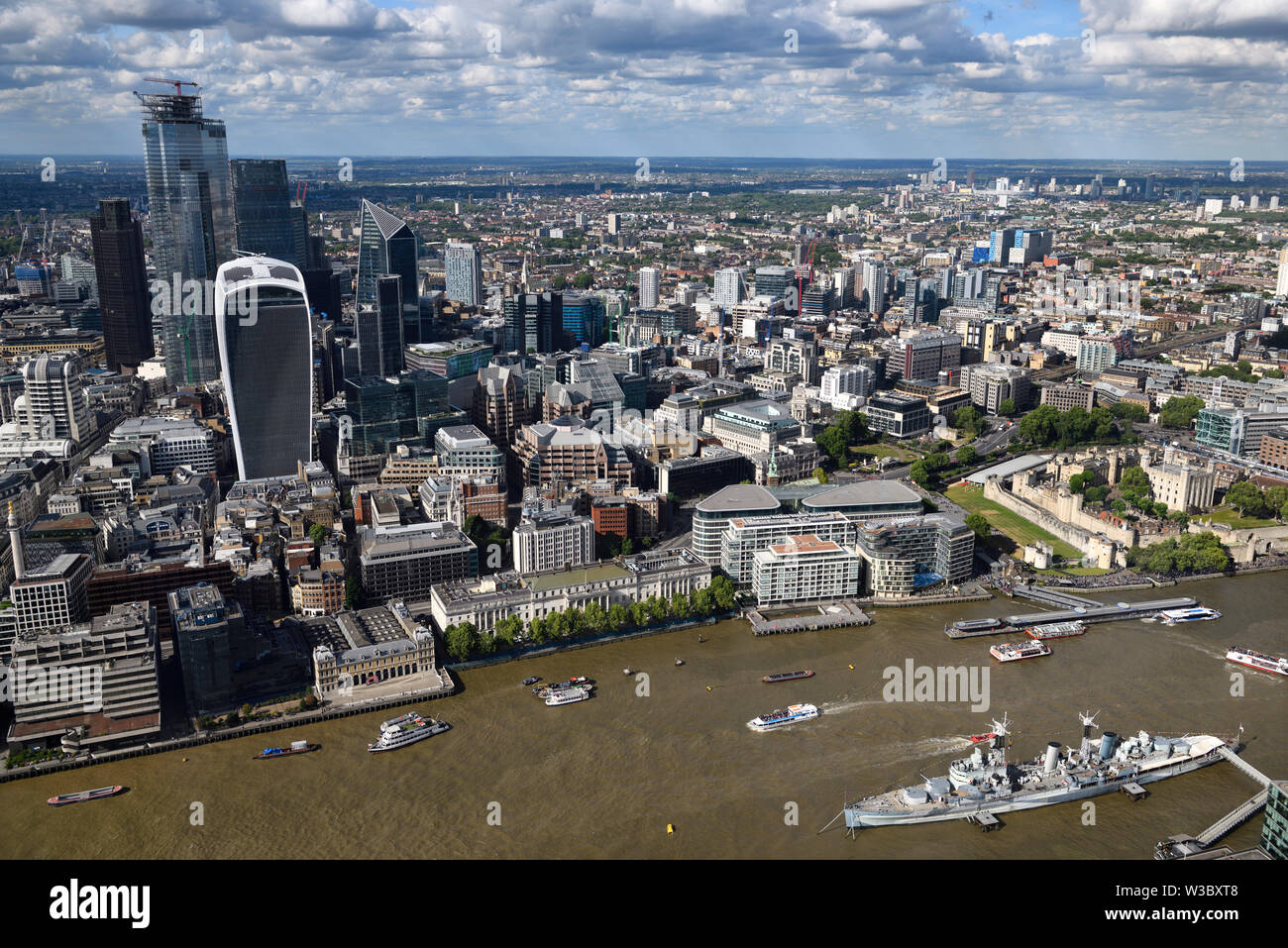 Aerial view of financial district skyscrapers on the muddy River Thames with Tower of London Castle and HMS Belfast warship London England Stock Photo