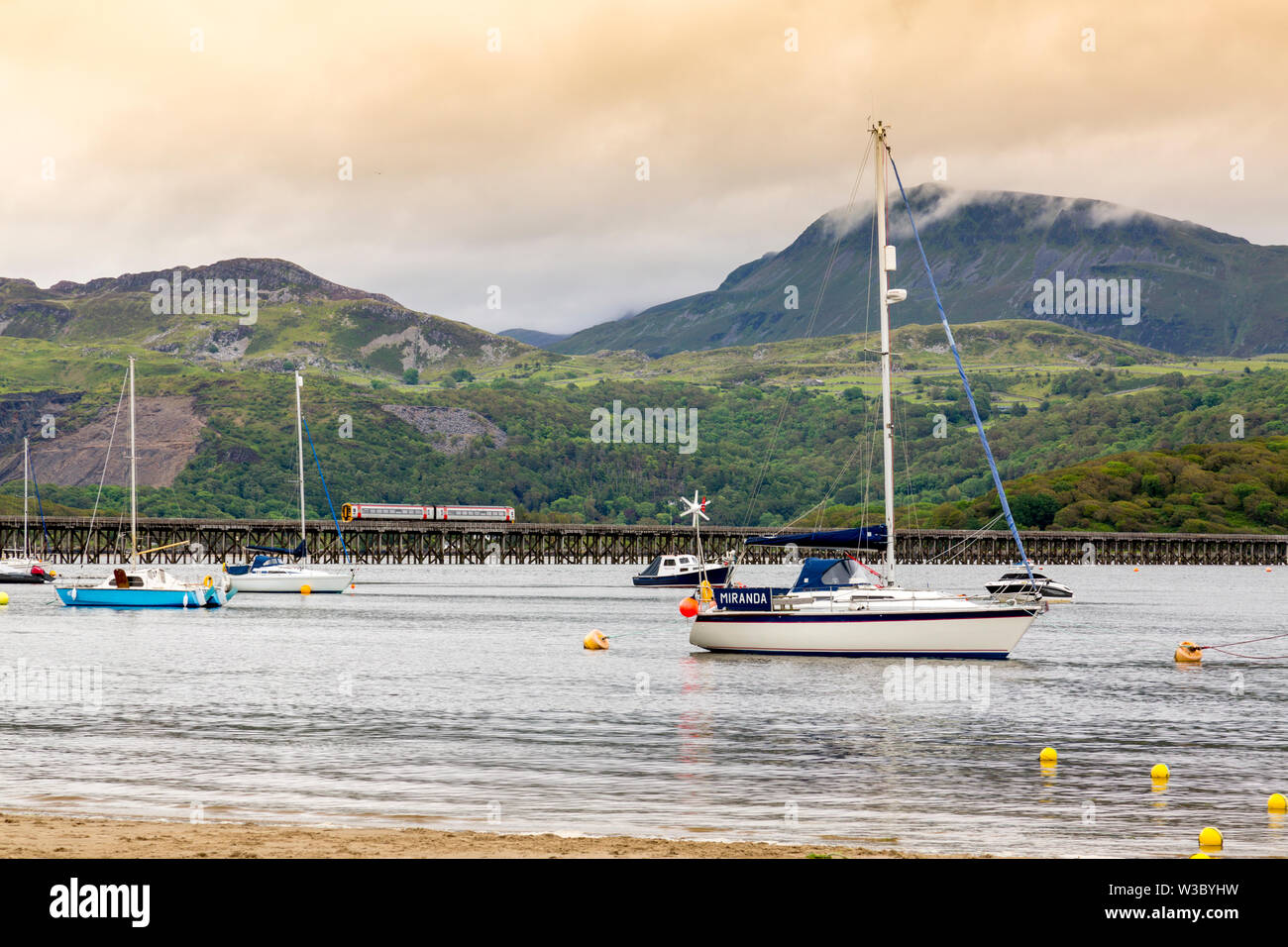 A Pwllheli to Dovey Junction local service crosses the historic bridge over the Mawddach estuary in Barmouth, Gwynedd, Wales, UK Stock Photo