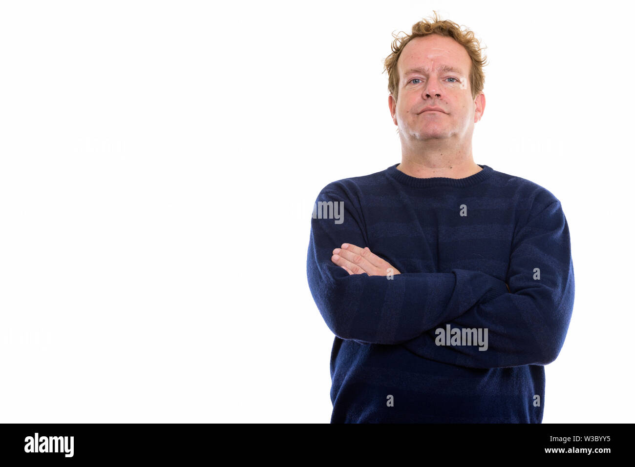 Studio shot of mature man with curly hair and arms crossed against ...