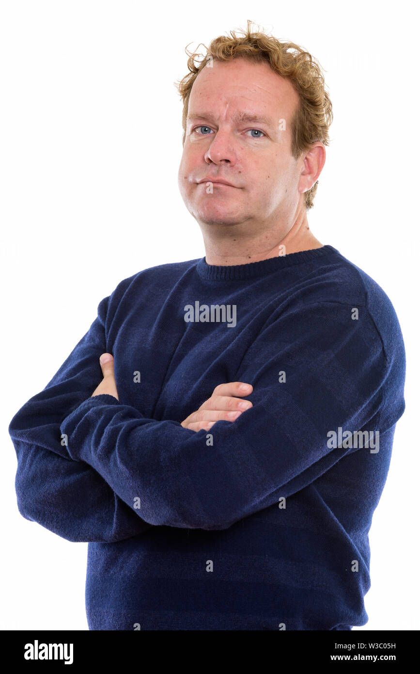 Studio shot of mature man with curly hair with arms crossed looking at ...