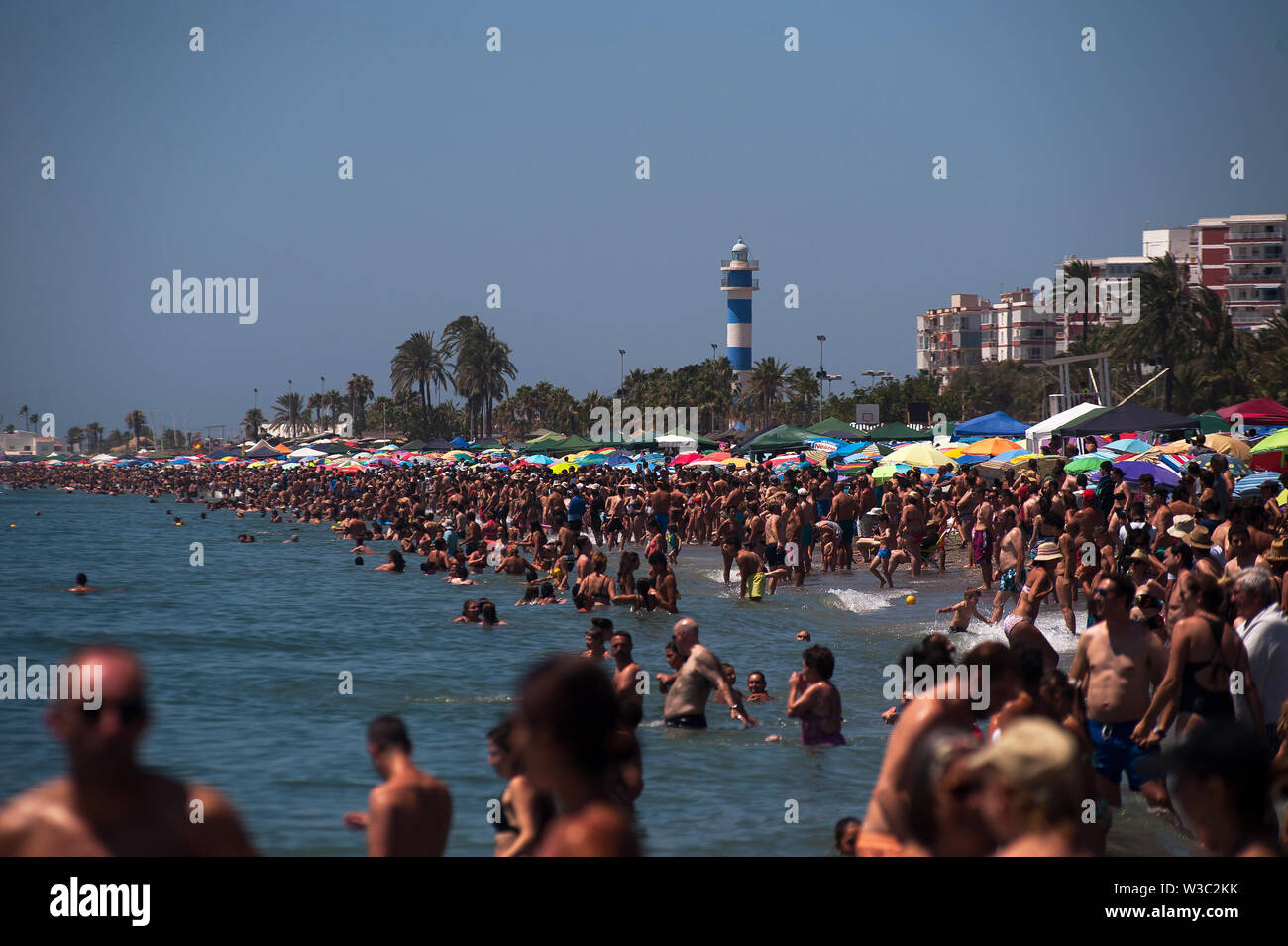 People enjoy the exhibitions of the Airshow on a hot summer day at a beach during the festival.The 2019 International Torre del Mar Airshow Festival is being hosted on 12,13 and 14 of July this year, attracting over 300,000 spectators. Members of different patrols perform with exhibitions and acrobatics during the festival. Stock Photo