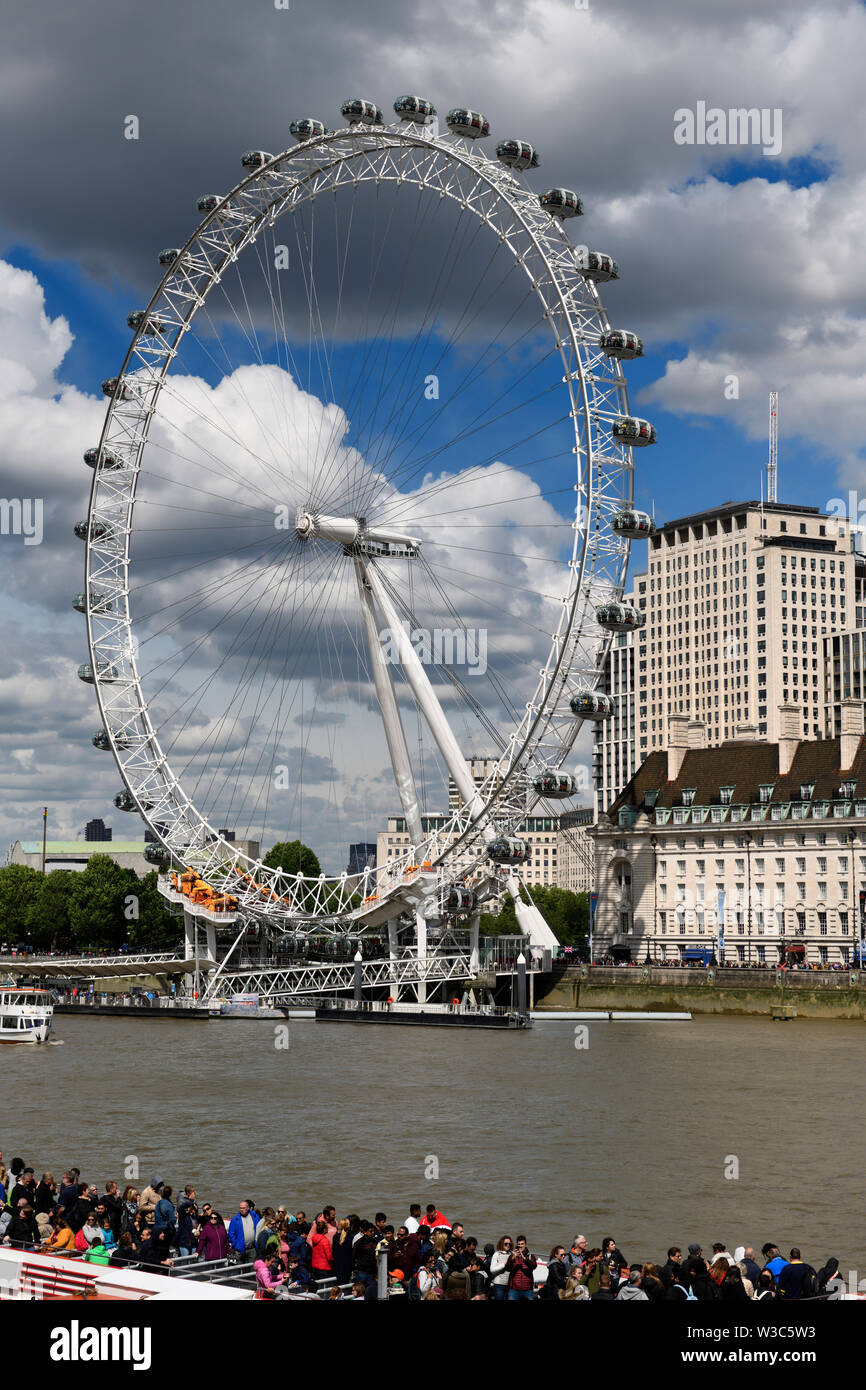 Tourists lined up for London Eye on the River Thames and on tour boats at Westminster Pier London England Stock Photo