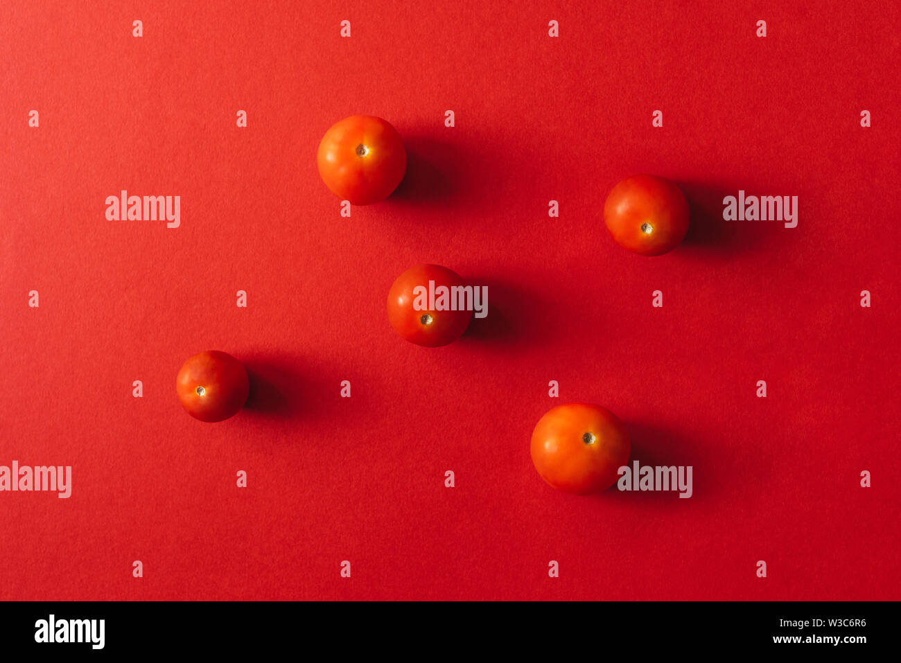 Five cherry tomatoes on a red background. Stock Photo