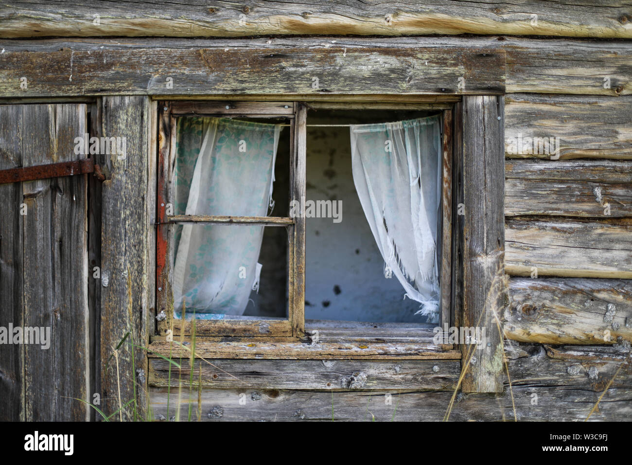 Broken window of an old weathered log sauna building at abandoned farmstead in Ylöjärvi, Finland Stock Photo