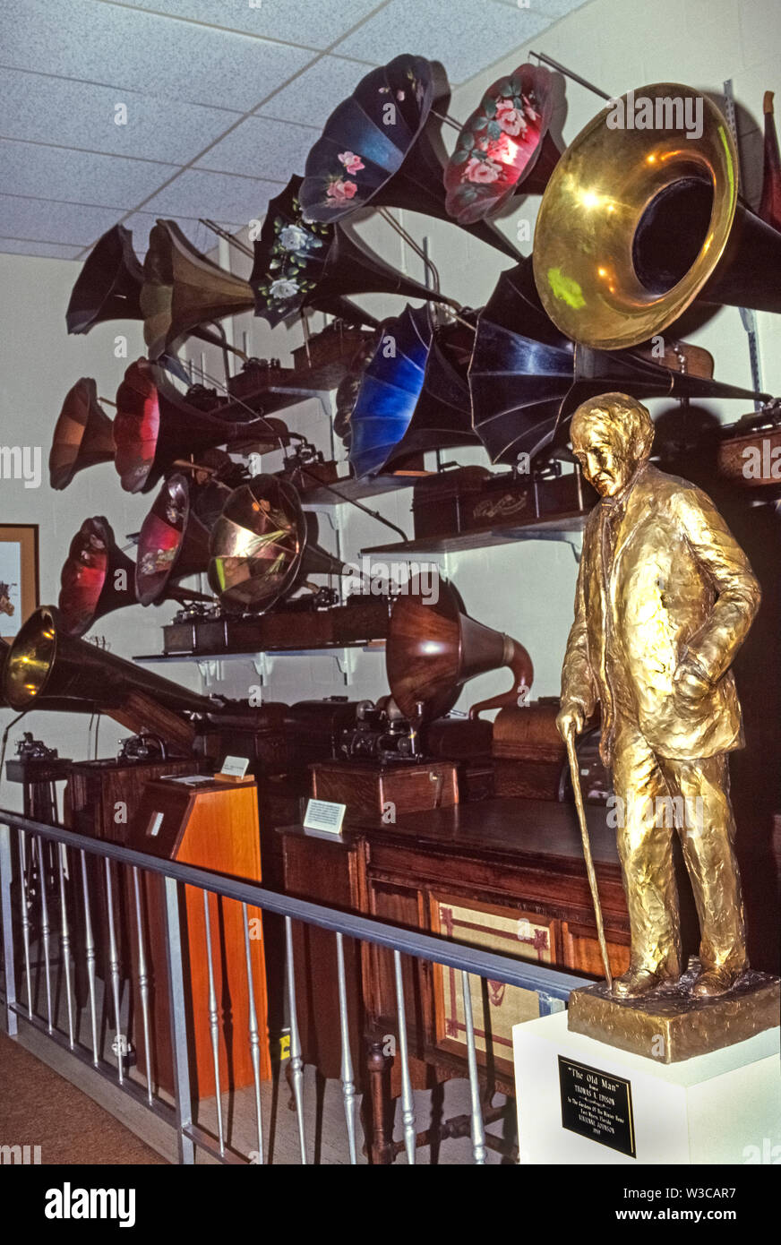 A golden-colored bronze statue of Thomas Alva Edison, the American inventor of the phonograph in 1877, is displayed with some early phonographs at his former winter estate in Fort Myers, Florida, USA. That 21-acre property is now a sprawling historical museum where visitors can also see other famous Edison inventions, including incandescent light bulbs and the motion picture camera. While his initial phonograph used a rotating cylinder covered with tinfoil to record and play back sound, later models utilized wax-coated cylinders and were fitted with large horns to amplify the sound. Stock Photo