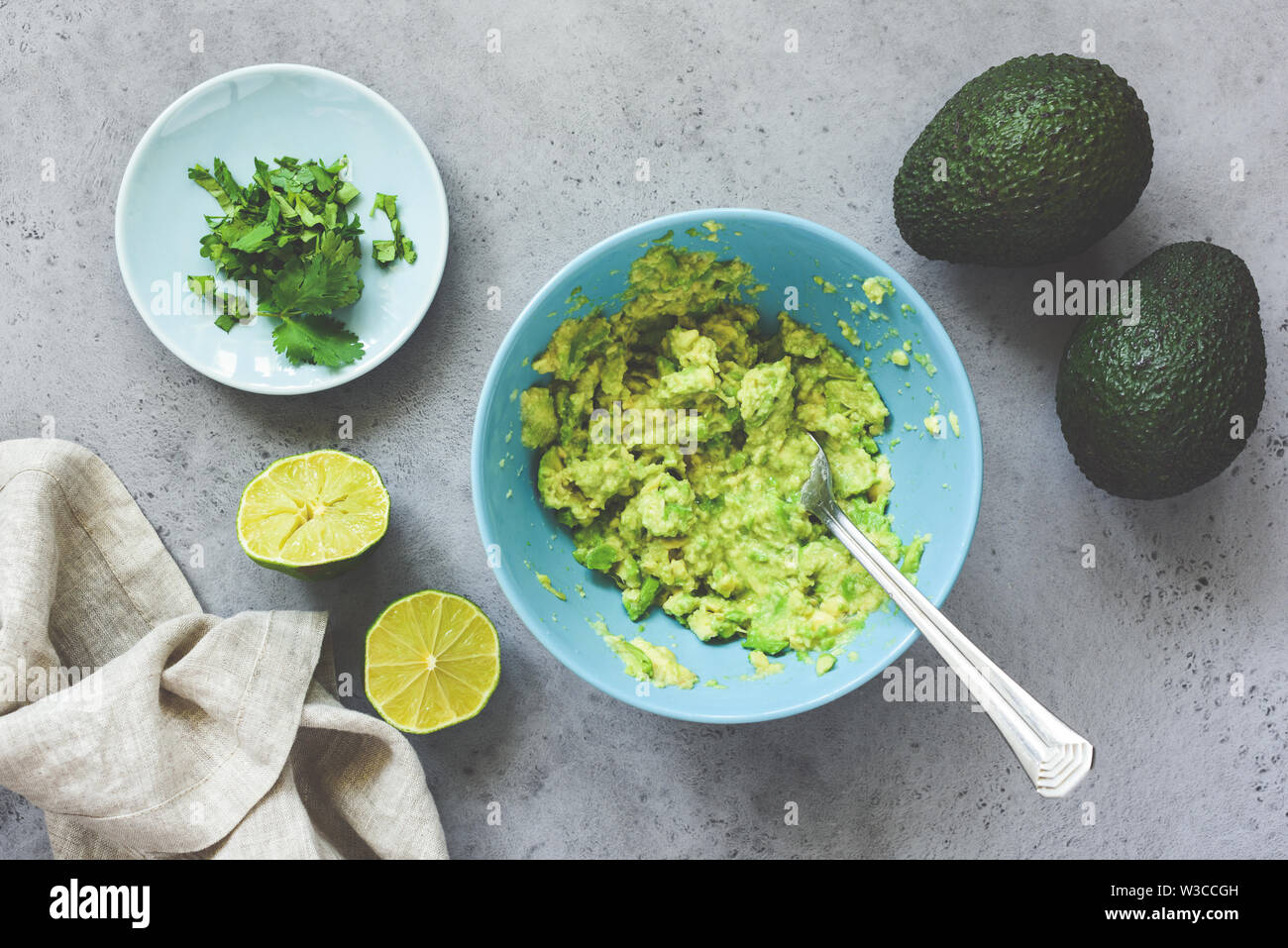 Mashed avocado guacamole sauce in blue ceramic bowl on grey concrete background. Table top view. Healthy vegan vegetarian food, spread for bread or to Stock Photo