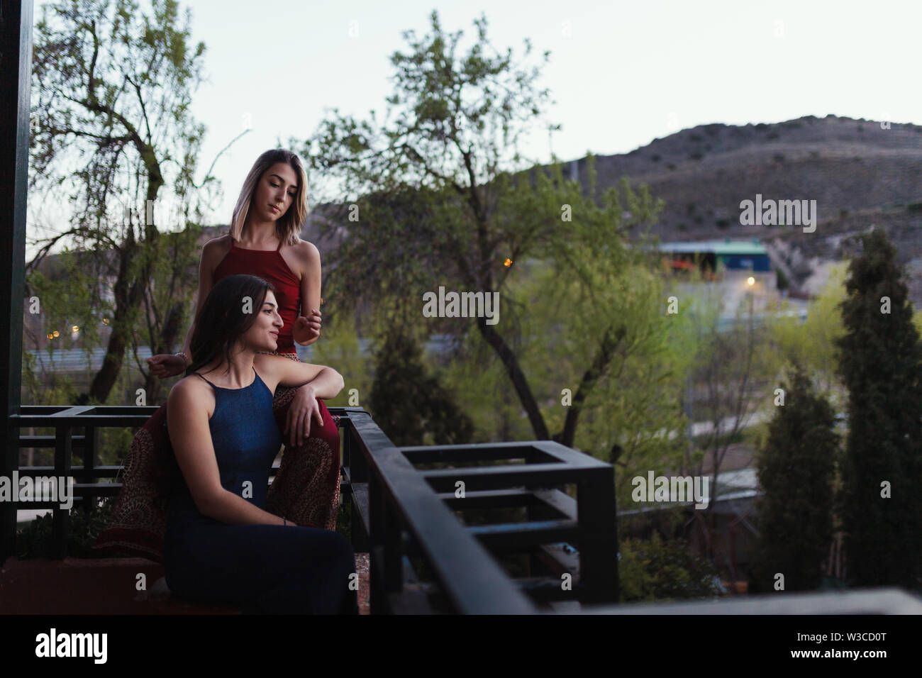 Two young caucasian women watch the sunset from their balcony. Stock Photo