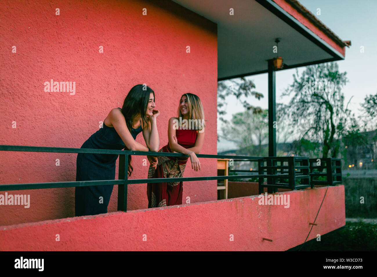 Two young caucasian women watch the sunset from their balcony. Stock Photo