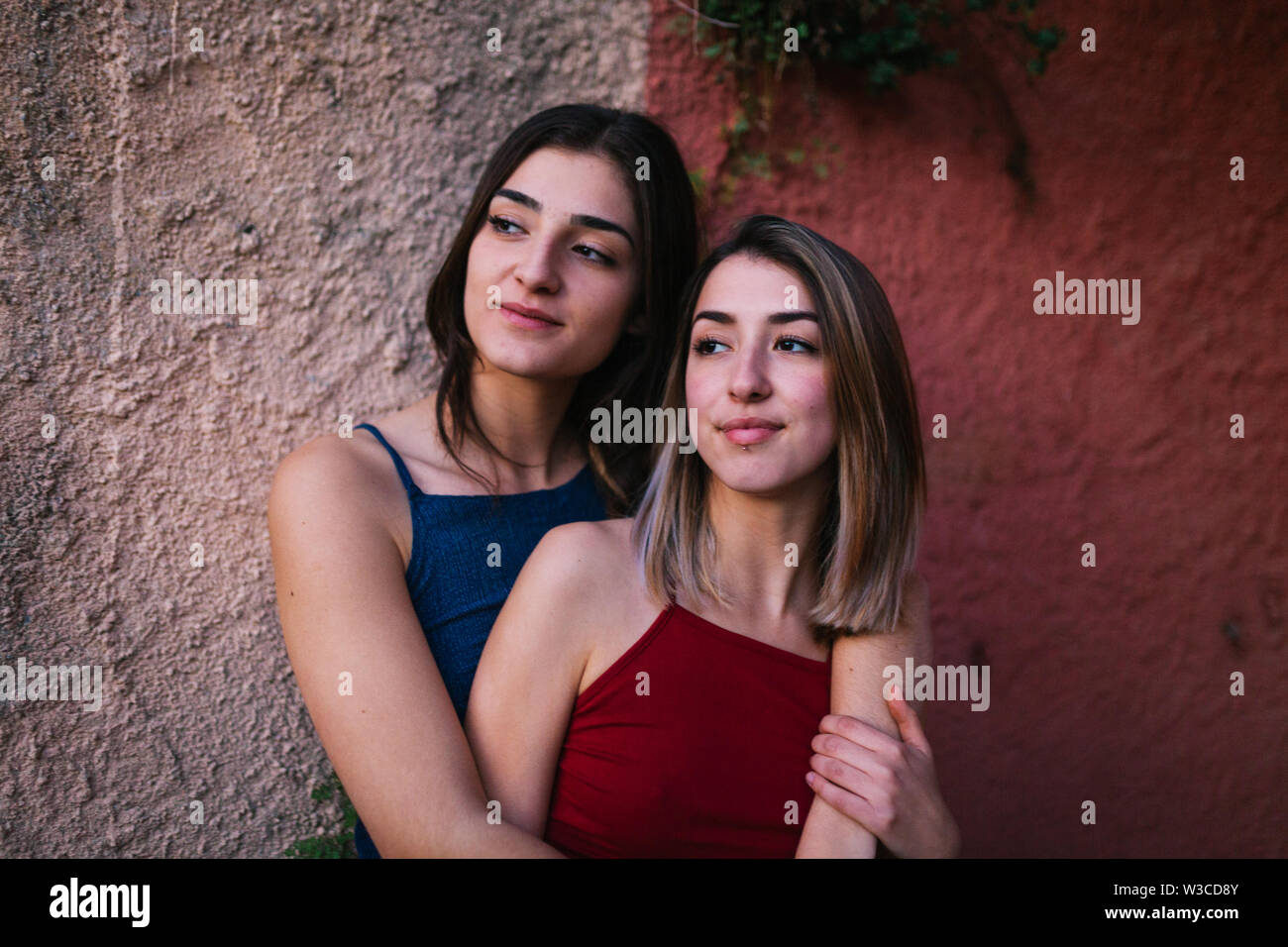 Two young caucasian women watch the sunset from two colors wall Stock Photo