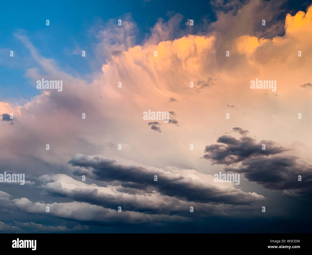 Dramatic evening sky with orange and dark storm clouds against the blue sky. Concept of upcoming storm and beautiful backdrop Stock Photo