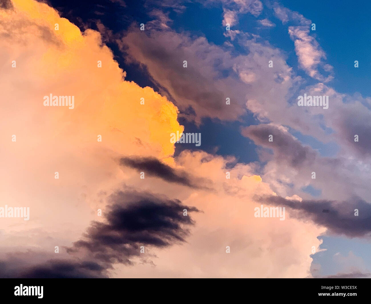 Dramatic evening sky with orange and dark storm clouds against the blue sky. Concept of upcoming storm and beautiful backdrop Stock Photo