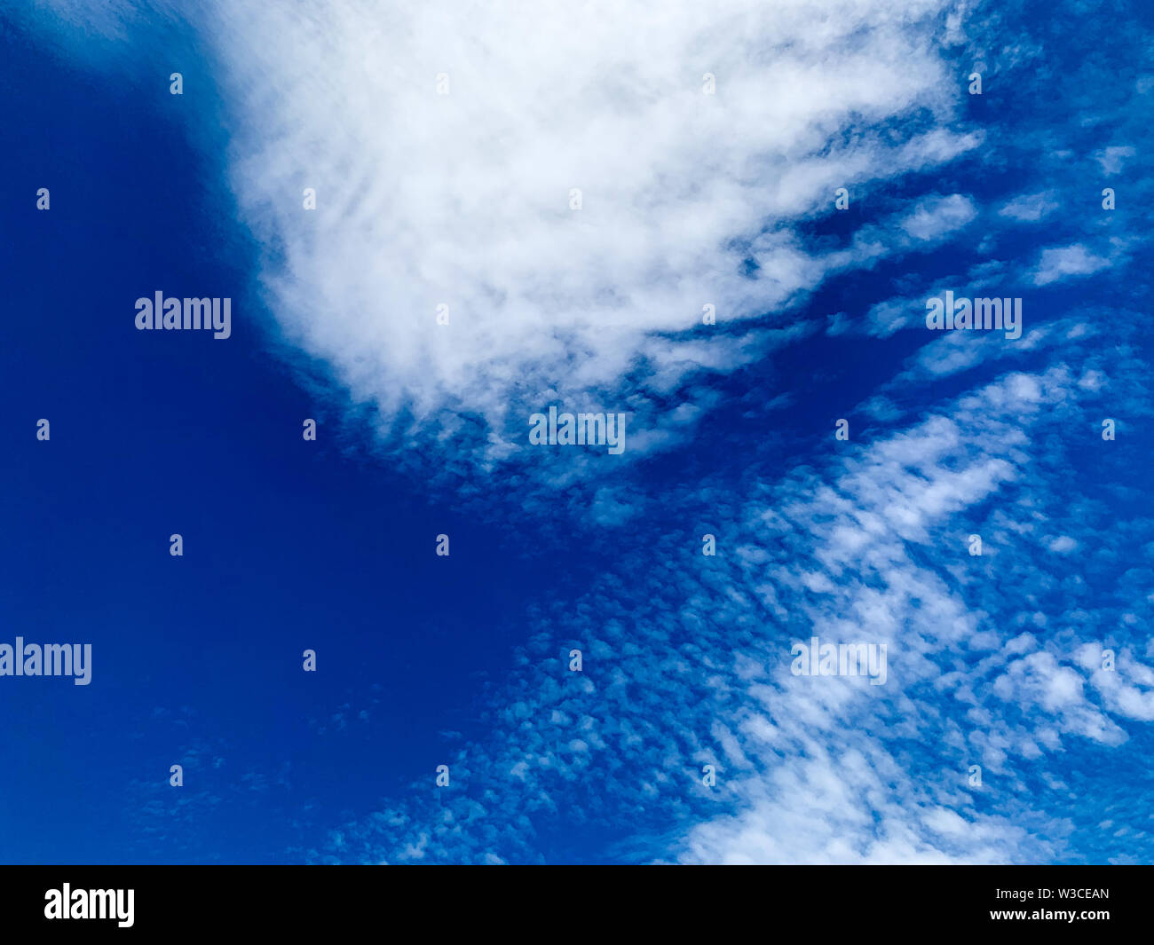 Cirrocumulus clouds are small rounded puffs that usually appear in long rows high in the sky. Cirrocumulus are usually white, but sometimes appear gra Stock Photo