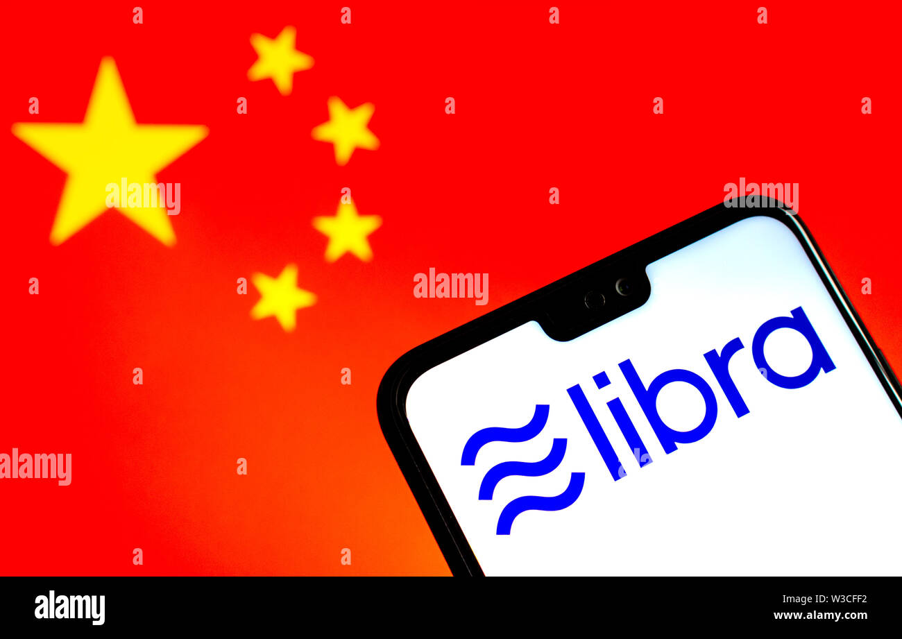 Facebook Libra crypto currency logo on the smartphone and blurred flag of China at a laptop screen on the background. Conceptual photo. Stock Photo