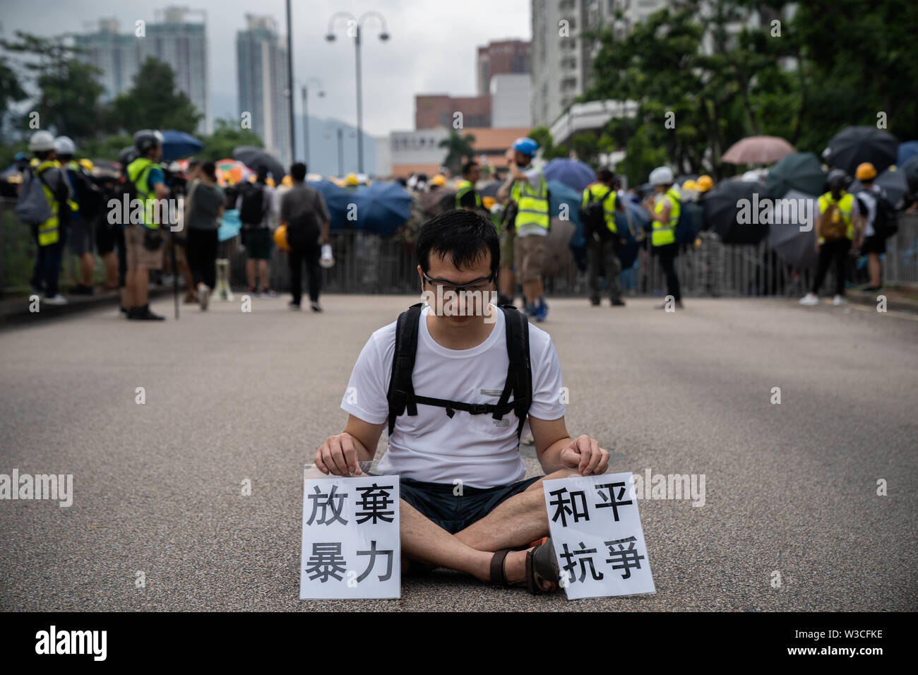 A demonstrator sits in between the protesters and the police during the protest.Thousands of pro democracy demonstrators took to the street once again in a new wave of anti government demonstrations which sparked by the extradition bill that the Hong Kong government was trying to push forward in June 2019.Police has made at least 30 arrests as protesters clashed with the riot police in the evening. Stock Photo