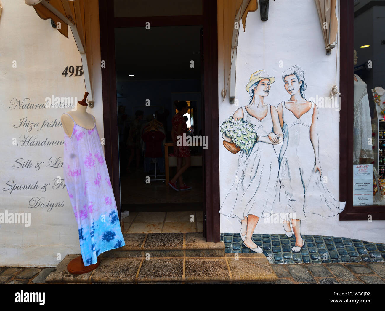Ladies cloths shop front with painted figures of women on wall. Stock Photo