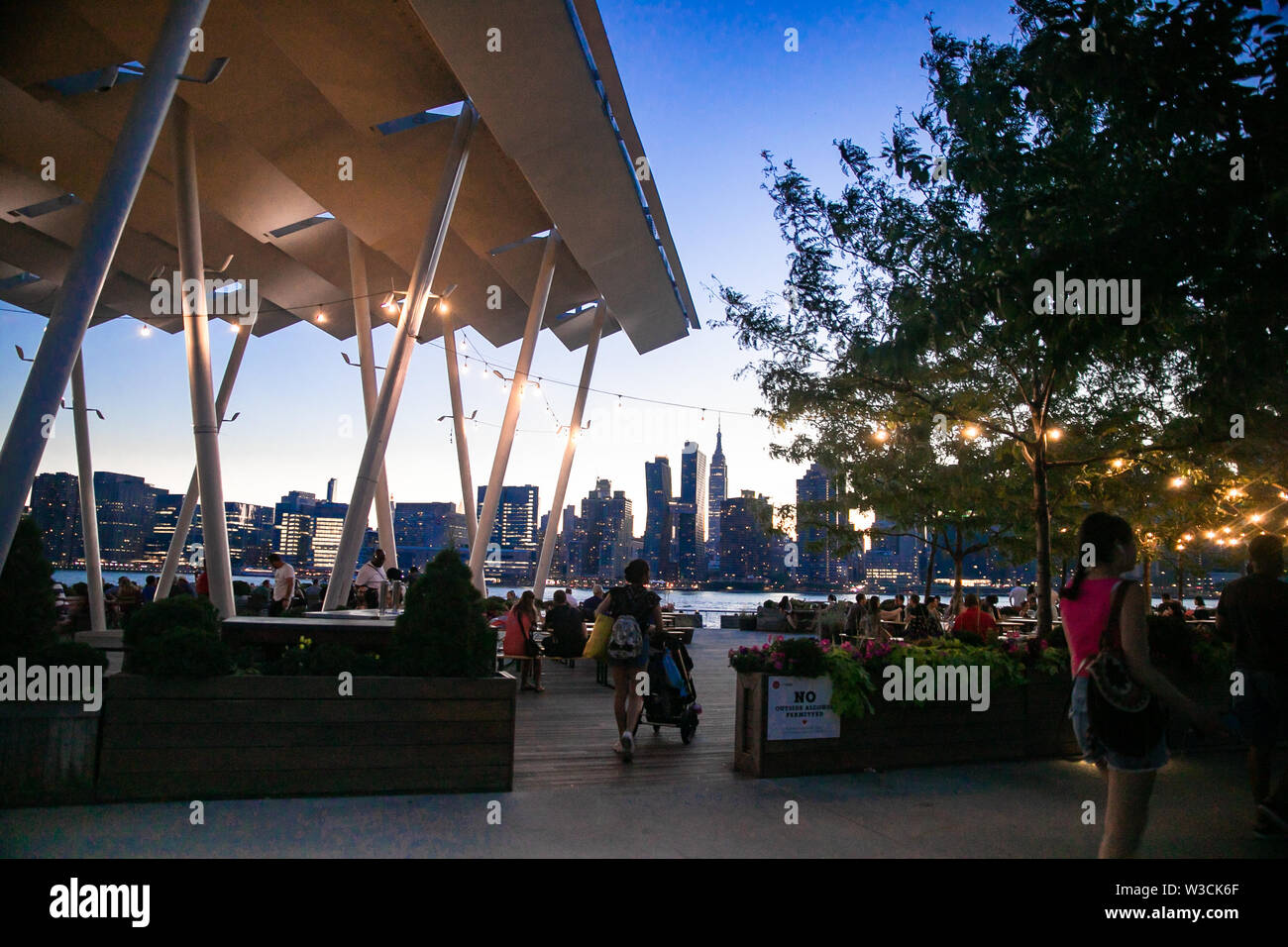 LONG ISLAND CITY, NEW YORK - JULY 13, 2019:  View at Gantry Plaza State Park on a summer evening with people visible. Stock Photo