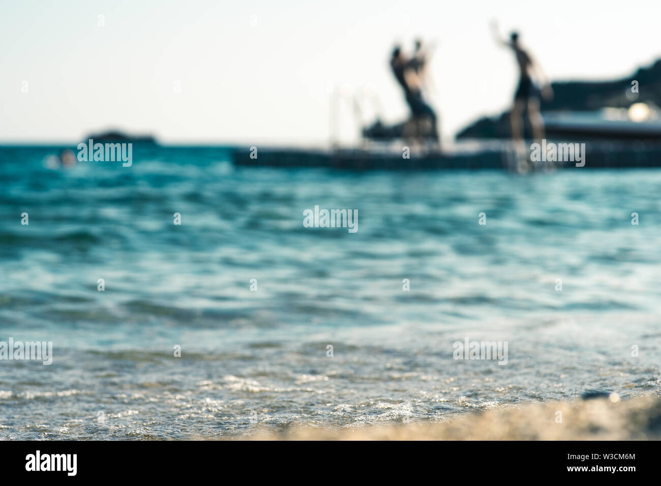 Floating platform in the mediterranean sea, with teenagers having fun, out of focus Stock Photo