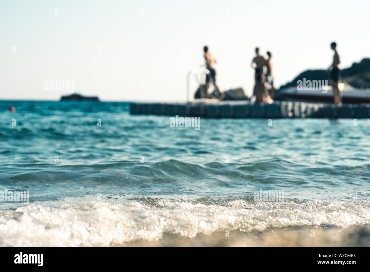 Floating platform in the mediterranean sea, with teenagers having fun, out of focus Stock Photo