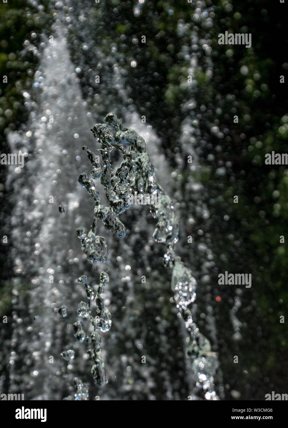 A jet of water droplets with a black blurred out background Stock Photo