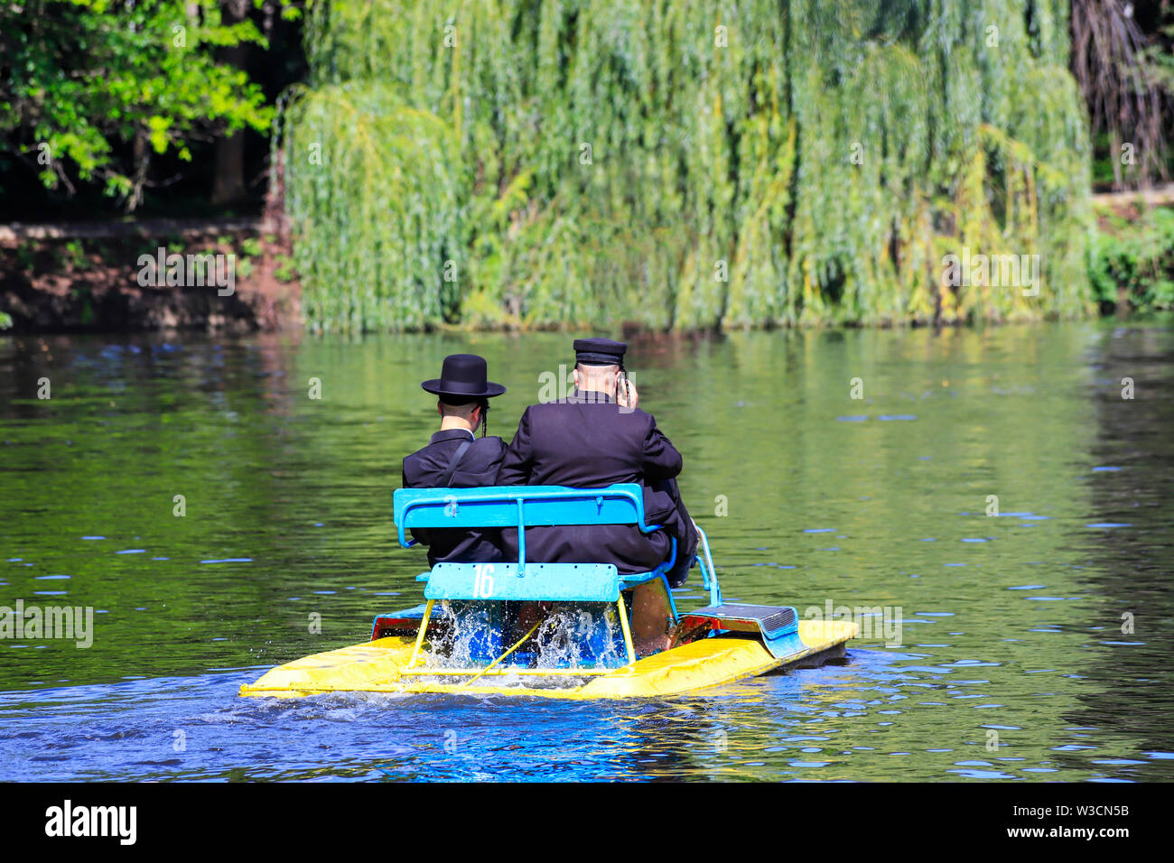 Religious Jew. 2 Hasidic Jews in traditional black clothes ride an old catamaran in the Park in Uman, Ukraine. Time of the Jewish New Year Stock Photo
