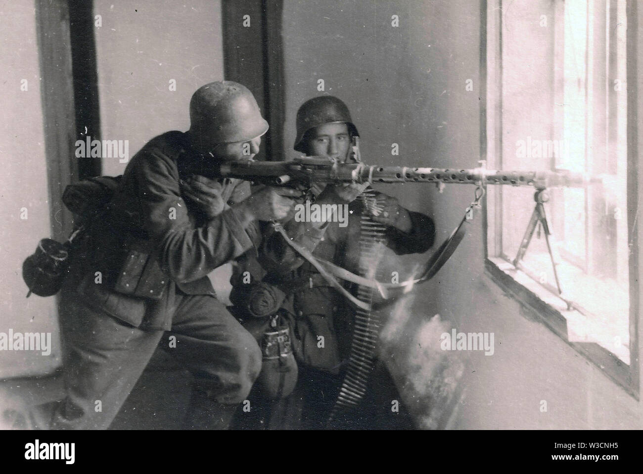 German Soldiers fire a Light Machine Gun MG34 from a window sill on the Russian Front 1942 Stock Photo