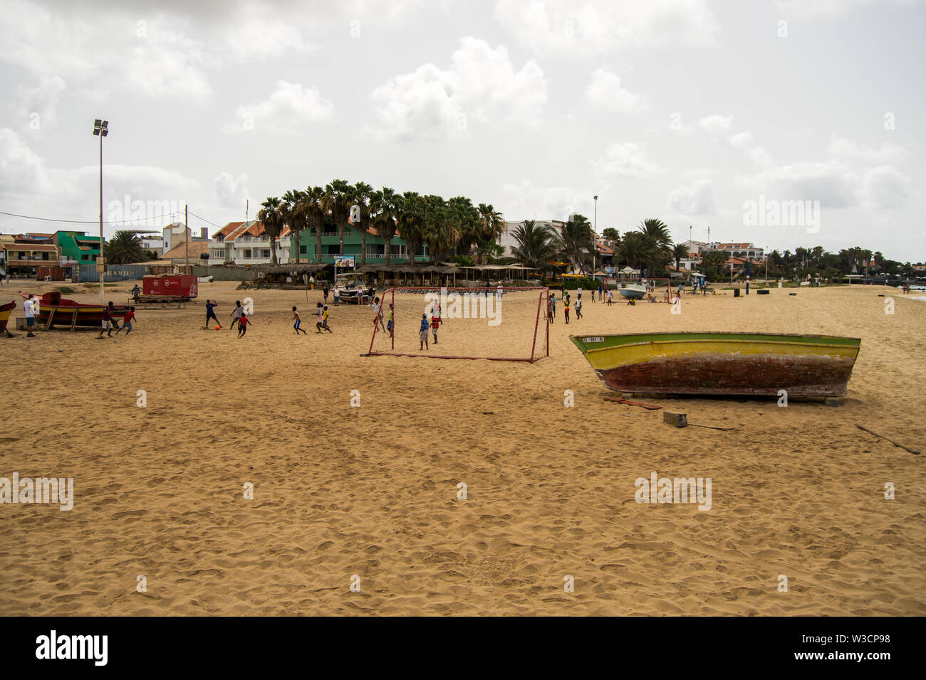 Cabo Verde, Cape Verde, Ilha do sal pontão praia de Santa Maria boat in the sand and kids playing football or soccer. Green Cape Island Kids. Stock Photo