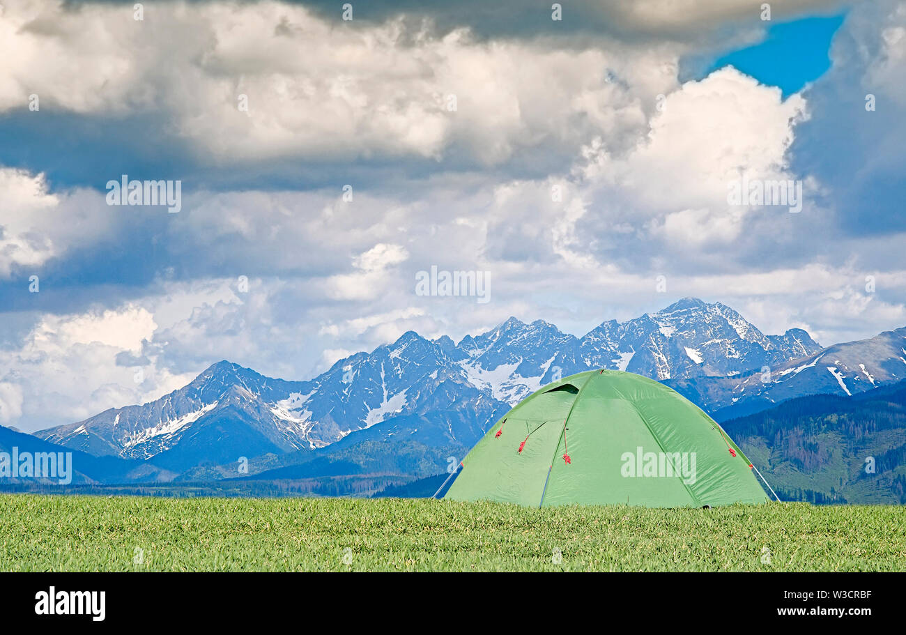 Tourist pitch a tent in summer mountains. Amazing green highland. Landscape photography Stock Photo