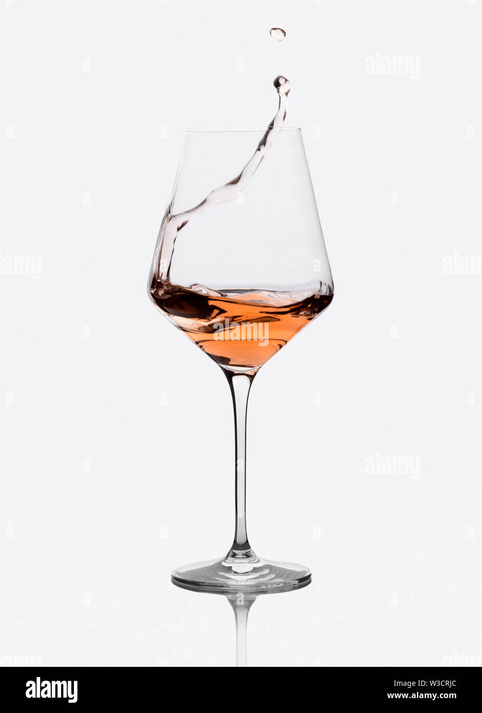 Glass of amber wine with splashes isolated on white. Stock Photo