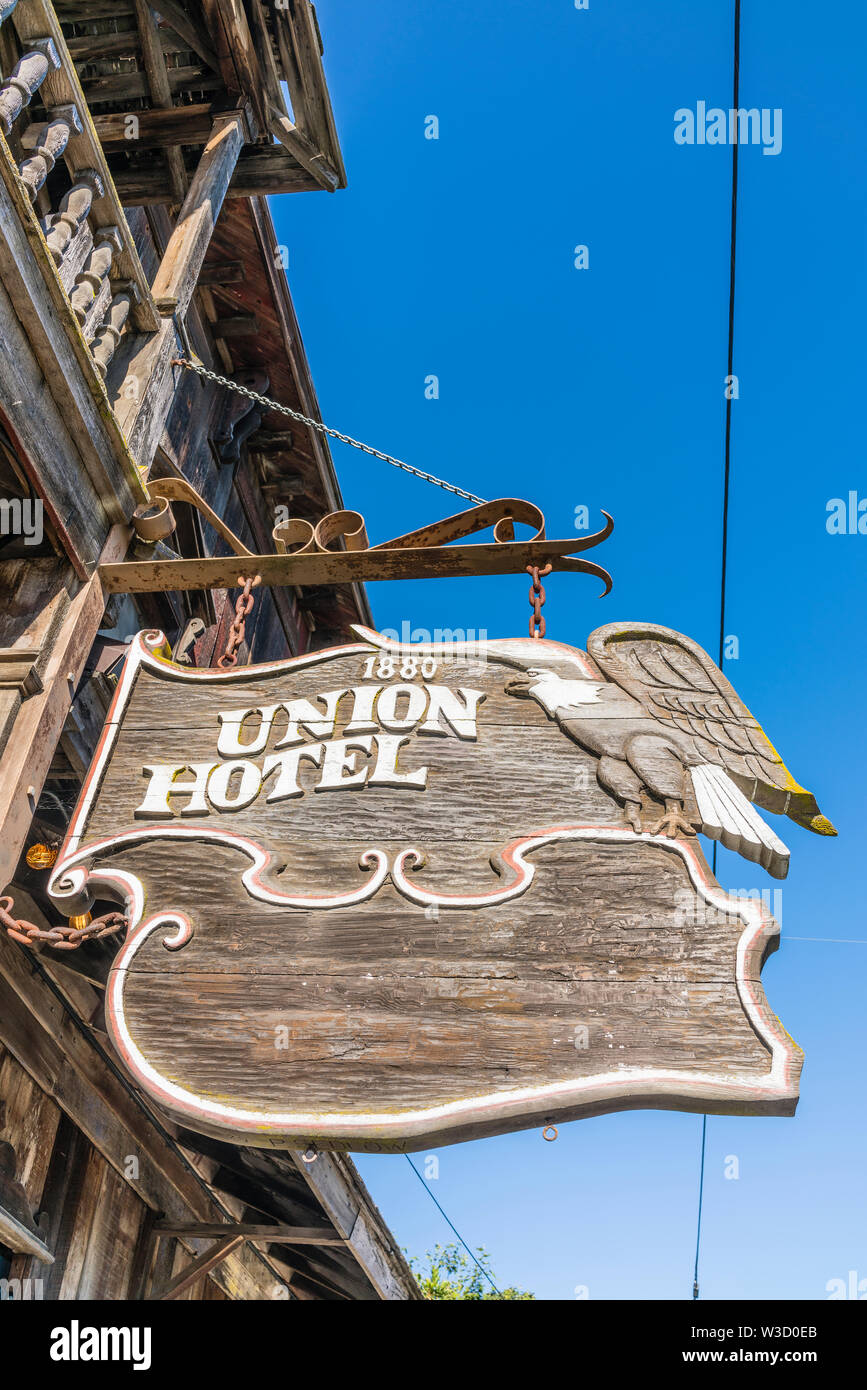 An old carved wooden sign for the historic Union Hotel in Los Alamos, California hangs from the front of the hotel over the wooden sidewalk. Stock Photo