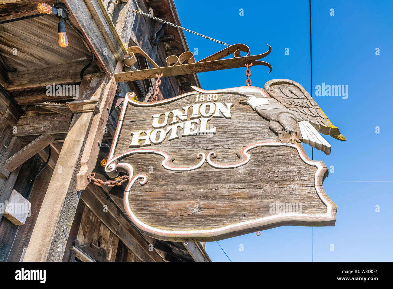 An old carved wooden sign for the historic Union Hotel in Los Alamos, California hangs from the front of the hotel over the wooden sidewalk. Stock Photo