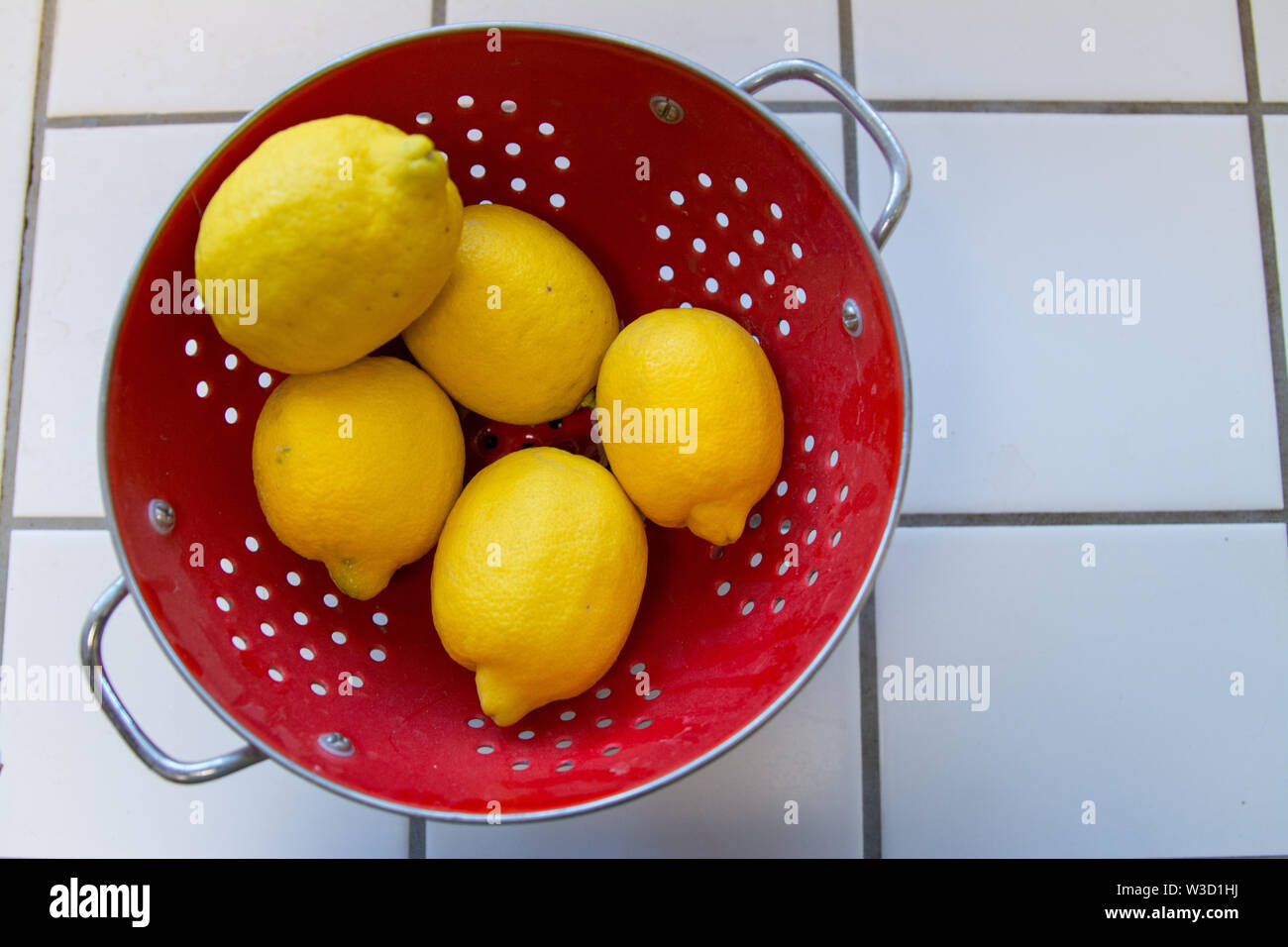 Large ripe lemons in a red colander Stock Photo - Alamy