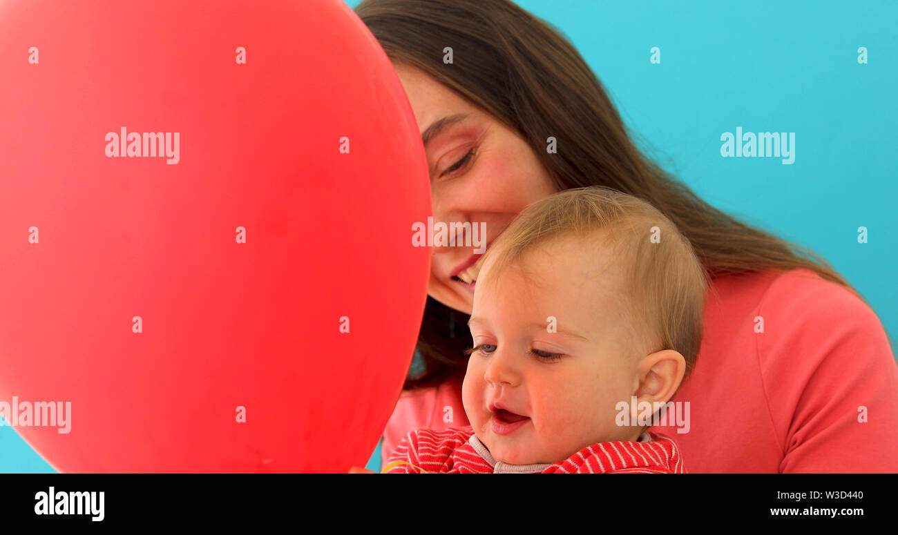 Smiling young woman with child holding balloon Stock Photo
